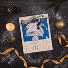 "When the Moon Hatched: The Official Colouring Book." Ein Buch mit einem weißen Drachen auf blauem Hintergrund, umgeben von Kerzen und Dekorationen.