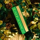 "THE WILD ROBOT" in gold auf grünem Buchrücken, umgeben von Tannenzapfen und gold-grünen Blättern.