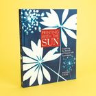 Buchcover mit weißen Blättern auf blauem Hintergrund, Titel "PRINTING WITH THE SUN".