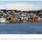 Kristiansund. März. Bunte Häuser an einem Hafen, dahinter eine Kirche. Berglandschaft im Hintergrund.