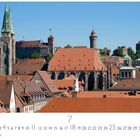 Nürnberg, Panorama. Kalenderansicht mit Monat Juli. Historische Gebäude mit roten Ziegeldächern, Türmen und einem klaren Himmel.