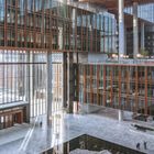 Ich kann keinen Text im Bild erkennen. Es zeigt eine weite, moderne Innenarchitektur mit Glaswänden und einem großen Hof.