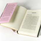 Eine aufgeschlagene Buchseite mit Überschrift "SCHWANENFEDERN" und ein rosa Einleger mit Text über einen Roman.