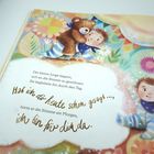 Der kleine Junge begann, sich an die Stimme zu gewöhnen. Sie begleitete ihn durch den Tag. Hab ich dir schon gesagt ... ich bin für dich da. Ein Junge umarmt einen Teddybären in bunter Szenerie.