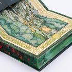 Ein Buch zeigt eine detailreiche Landkarte mit Pfaden und Wäldern, eingerahmt von einem kunstvollen Rand. Ein rotes Lesezeichen ist sichtbar.