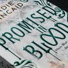"Promised in Blood" in grünen Buchstaben, darunter "Mein Blut entfacht dein Feuer." Elegante, verschnörkelte Muster.
