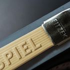 Auf einer Holzoberfläche steht "SPIEL", darüber ein Metallbügel mit "SEBASTIAN FITZEK". Teil eines Buchcovers.