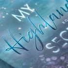 Texte: "MY Highland SECRET", "ROMAN". Hintergrund in Blau- und Lilatönen mit glitzernden Lichtpunkten.