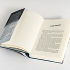 Der Text: "IN DER TODESZONE". Ein aufgeschlagenes Buch bei Seite 7 liegt auf weißem Untergrund.