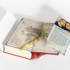 Eine Karte mit gelbem Lesezeichen in einem geöffneten Buch. Daneben ein Flyer mit Foto und Text über "Iny Lorentz".