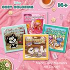 "COZY COLORING", "14+", "Mehr Cozy Moments mit Disney". Vier farbenfrohe Disney-Malbücher in einer gemütlichen Szene.