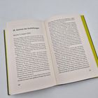 "36 Sommer der Enthüllungen, Ascona, 5. August 2023." Ein geöffnetes Buch auf einer weißen Oberfläche.