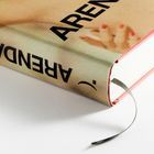 Arendalkopf zeigend. Hardcover-Buch mit rosafarbenem Einband, Lesezeichen und teilweise sichtbarem Bild einer Hand.