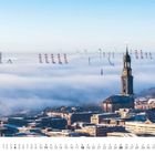 Text: "Juli", Kalenderdaten unten. Statement über Wahrzeichen, Häuser, Nebel und Kräne. Stadt mit Kirchturm in Nebel.