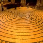 Ein riesiges Steinlabyrinth, kreisförmig angeordnet, in einer Kathedrale mit Menschen, die entlang der Pfade gehen.