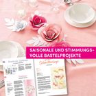 SAISONALE UND STIMMUNGSVOLLE BASTELPROJEKTE. Bunte, große Papierblumen auf einem gedeckten Tisch mit Tellern und Gläsern.