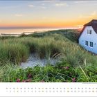 Juli-Kalender, Strohdachhaus rechts, Dünen und Gras, Sonnenuntergang über ruhigem Meer im Hintergrund.