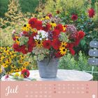 Kalenderseite für Juli. Ein bunter Blumenstrauß in einem Metalltopf auf einem Tisch im Garten.