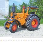 "Juli" oben, Kalenderdaten unten, orangefarbener Traktor auf Schotter vor grüner Kulisse.