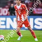 Text: Minjae Kim, Vorjahresabbildung. Ein Fußballspieler vom FC Bayern in rotem Trikot auf dem Spielfeld.