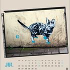 Kalenderblatt, oben links steht "JUL". Wandgemälde einer Katze mit blauen Pfotenabdrücken auf einem Gehweg.