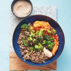 Ein Teller mit Quinoa, Brokkoli und Süßkartoffelpüree, daneben eine Schale mit cremiger Sauce auf hellblauem Untergrund.