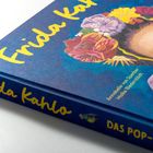"Frida Kahlo" in gelber Schrift auf blauem Buchcover, Blumen im Haar. Zeichnung eines Papageis auf der Vorderseite.