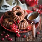 Juli 7, Montag bis Sonntag. Mehrere kleine Schokoladenkuchen auf rotem Teller, dekoriert mit roten Johannisbeeren.