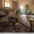 Kalenderblatt Juli 2021. Verlassenes Friseurstudio mit kaputtem Sessel, alten Trockenhauben und abblätternder Wandfarbe.