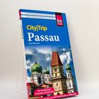Reiseführer mit dem Titel „City|Trip Passau“ von Sven Eisermann, zeigt historische Gebäude mit Türmen unter blauem Himmel.