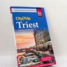 Reiseführer "City|Trip Triest" mit Bild eines Hafens bei Sonnenuntergang. Boote und Gebäude mit Cafés am Ufer.