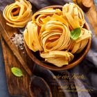 Zitat von Roman Polanski über das Kochen. Juli-Kalender, gelbe Tagliatelle-Nester in einer Holzschale, Basilikumblatt.