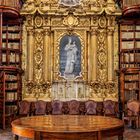 Zitat von Hermann Hesse über die Welt der Bücher. Monat Juli Kalender vor prächtigem Bücherregal mit vergoldetem Altar.