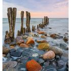 06 FEBRUAR, MO 08 DI 09 MI 10 DO 11 FR 12 SA 13 SO 14; Strand mit Holzpfählen und bunten Steinen.