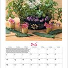 „Juli“ steht in pinker Schrift über einem Kalender. Ein Topf mit Koriander und Blumen steht auf einem Holztisch.