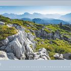 Juli 2027. Ein felsiger Bergpfad mit grünen Pflanzen im Vordergrund, dahinter weite Berglandschaft und klarer Himmel.