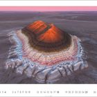 Kalenderseite mit Juli-Datum. Ein Berg erscheint mit bunten, schichtartigen Gesteinsformationen in der Wüste.