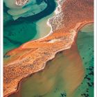 "Juli" steht unten. Luftaufnahme mit türkisfarbenem Wasser und einer rot-braunen Landzunge.
