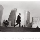 "FRANCE, Paris, 2009, La Défense." Ein Geschäftsmann in Anzug geht vor modernen Hochhäusern entlang.