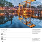 Juni/Juli, Monatsübersicht. "Lange Vechtbrug" Zugbrücke in Weesp, reflektiert im Wasser, abendliche Beleuchtung.