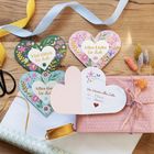Herzförmige Karten mit Blumen, Texten "Viel Glück für dich" und "Von Herzen alles Liebe", dekoriertes Geschenk daneben.