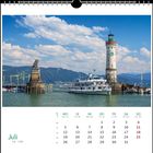 Juli. Kalenderblatt mit Schiff, Leuchtturm und Löwenstatue am Wasser. Malerische Berglandschaft im Hintergrund.