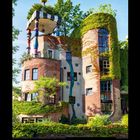 Zahlen von 1 bis 31 unten, Monat VII 2027. Ein ungewöhnliches, buntes Gebäude mit Pflanzen.