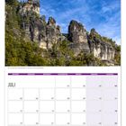 Kalender für Juli; Tage beginnen mit Montag. Foto: Felsformation mit Brücke unter blauem Himmel und Bäumen.