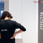 Texte: „Ofri Lapid“, „Mất chữ“, „Purple.“ Eine Person in schwarzem Shirt betrachtet etwas in einer Galerie.