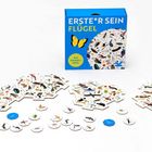Text: "ERSTE*R SEIN FLÜGEL EIN WIMMEL-SPIEL". Spiel mit Tierillustrationen auf Sechseck-Karten und kleinen Chips.