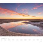 Juli 2027 | Am Meer. Kalenderansicht mit Landschaftsfoto: Wasser, Sand, und ein dramatischer Sonnenuntergang.