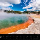 Neuseeland 07; Wai-O-Tapu Thermal Wonderland, Rotorua. 

Heiße Quelle mit orangefarbenem Rand und grünem Wasser, darüber Dampf. Berglandschaft im Hintergrund.