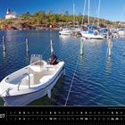 Text: Schweden 07; Sommertag an der westschwedischen Schärenküste. Boote im Wasser, Hintergrund: Hügel, rote Häuser, Kirche.