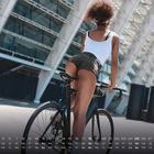 Kalenderdaten unten platziert. Eine Frau in Shorts und Tanktop fährt ein Fahrrad vor moderner Architektur.